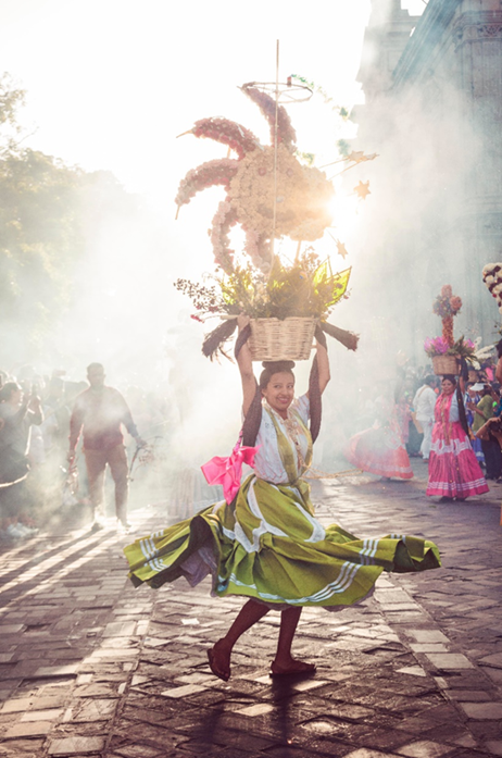 Local woman, with a colorful skirt, dancing with a basket on her head during the Guelaguetza celebrations in Oaxaca, Mexico, a festival that is known to showcase indigenous traditions and attracts a considerable amount of tourism flow. 