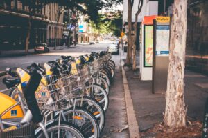 Bright yellow CityCycle bikes are lined up next to the pavement on an urban road in Brisbane, Australia. The popularity of sustainable forms of travel have made these bike rental companies much more common throughout the world. Photo by ZACHARY STAINES on Unsplash.